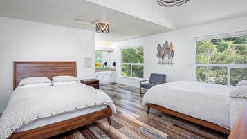 Quarto com duas camas, piso de madeira, uma janela grande e luminária no teto.