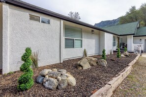 A house with a white exterior, a green roof, and a landscaped garden with rocks and small trees. - "Sierra River House" on the Main Fork of the Kaweah River.  Breathtaking Views! (Three Rivers)
