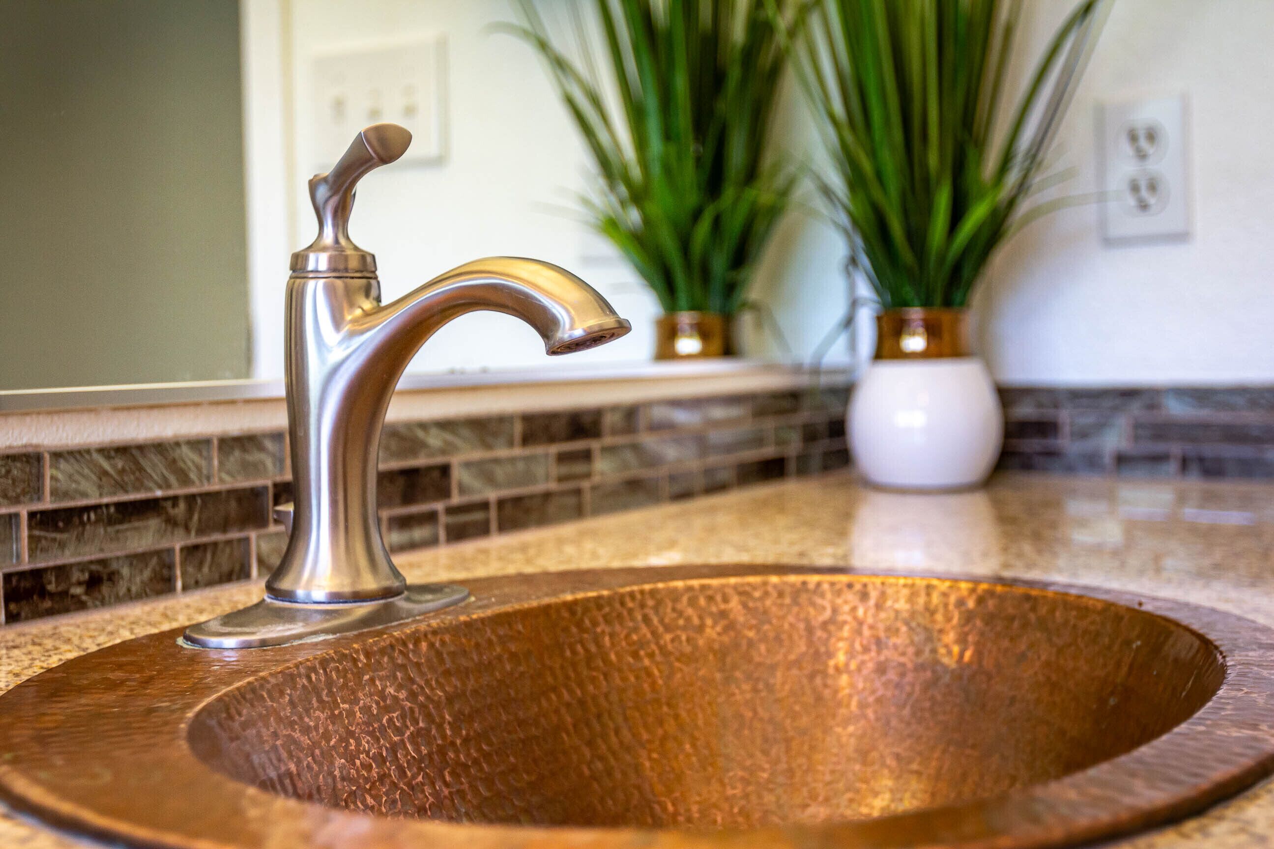 A kitchen sink with a modern faucet and a copper basin.