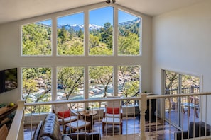 A spacious room with a large window overlooking a mountainous landscape and a river.