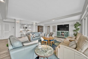 Un salon moderne comprenant un canapé, des fauteuils, une table basse et un téléviseur.