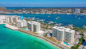 A coastal hotel with multiple high-rise buildings, a marina with boats, and a clear view of the ocean.