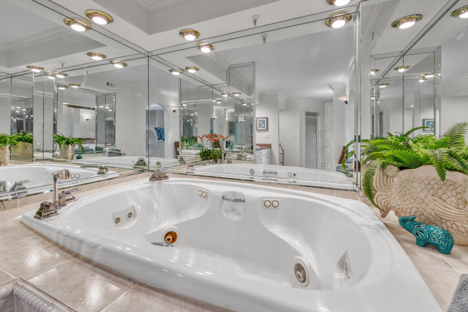 A modern bathroom with a large freestanding bathtub, multiple mirrors, and a decorative headboard.