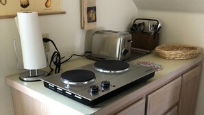Une cuisine équipée d’un plan de travail, d’un grille-pain, d’une bouilloire et d’un tableau représentant des champignons, accroché au mur.