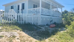 Een gelijkvloers huis met een veranda en een witte picket fence.