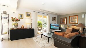 Una sala de estar moderna con un sofá, una mesa de centro, un televisor y una estantería.