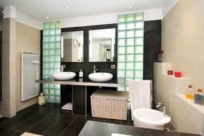 A modern bathroom with two sinks, a large mirror, and a toilet.