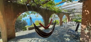 Un hamac suspendu entre des arches de pierre, offrant une vue sur la mer.