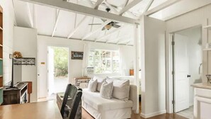 Un vaste espace de vie avec un canapé blanc, un plancher en bois et un ventilateur de plafond.