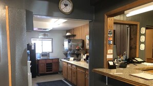 A kitchen with wooden cabinets, a microwave, a coffee machine, and a clock on the wall. - Campbell Lodge (Glasgow)