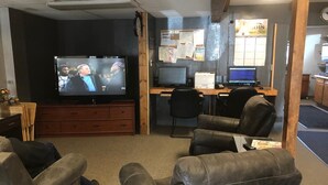 A living room with a TV, leather chairs, a desk with computers, and a bulletin board. - Campbell Lodge (Glasgow)