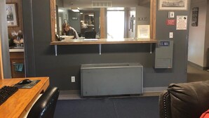 A reception area with a desk, computer, and a large mirror. There is a U.S. Mail box and a small refrigerator. - Campbell Lodge (Glasgow)