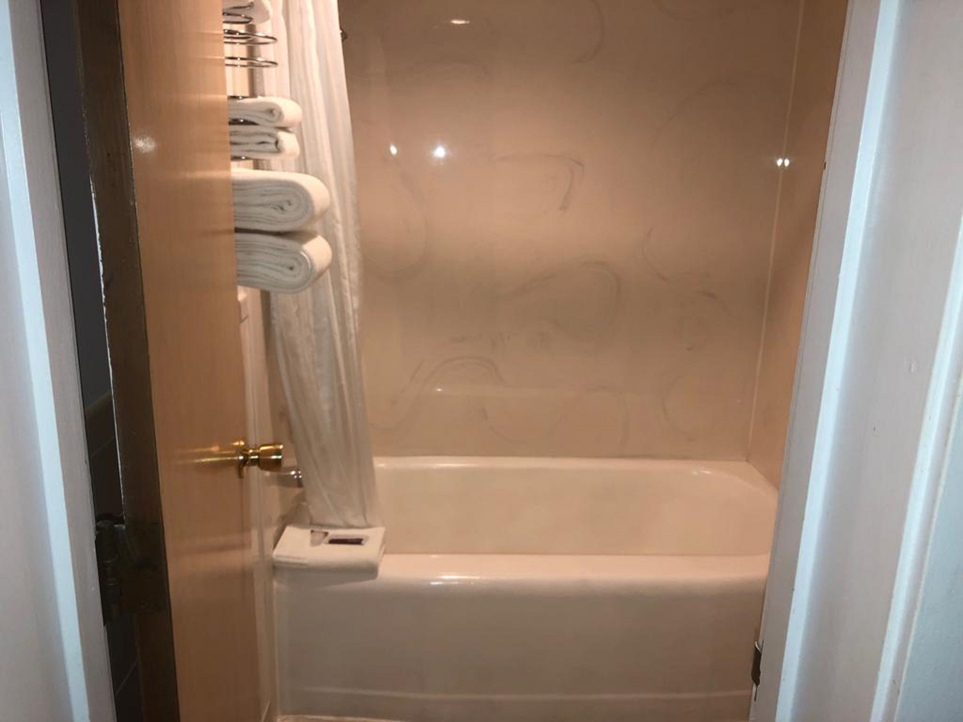 A bathroom with a bathtub, a towel rack with folded towels, and a toilet.