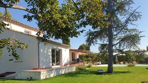 Un bâtiment blanc avec un toit en tuiles, un patio couvert et une pelouse verdoyante.