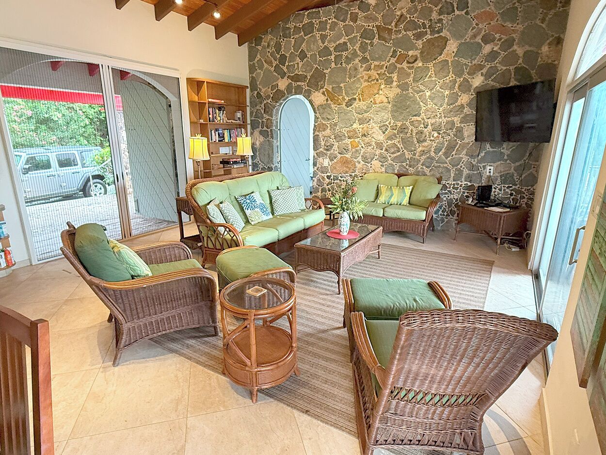 A cozy living room with wicker furniture, a stone wall, and a television.