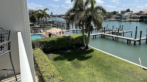 A view of a marina with boats docked, a swimming pool, and a palm tree.