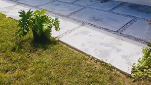 Uma casa com varanda coberta, rede e plantas em vasos.