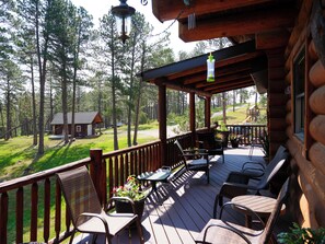 A wooden deck with outdoor furniture, surrounded by a forest.