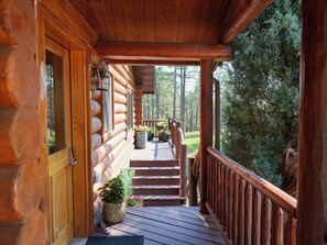 Une cabane en bois avec un porche, une porte et une fenêtre.