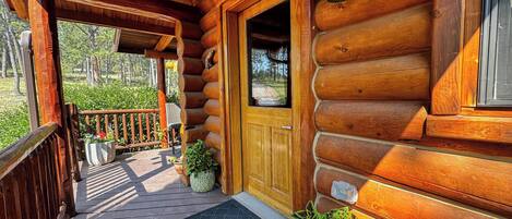 A wooden cabin with a porch, a door, and a window.