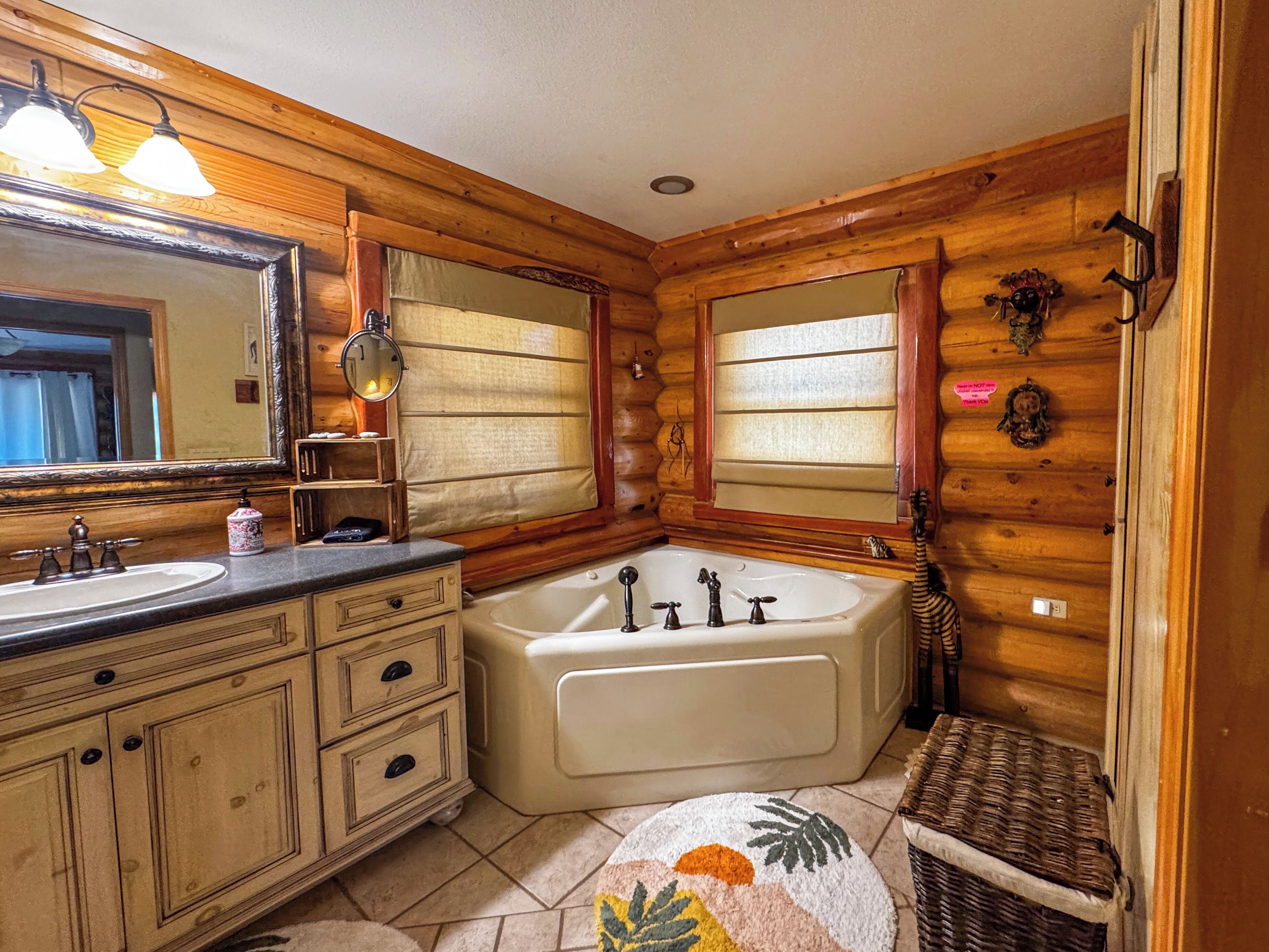 A wooden cabin bathroom with a sink, vanity, and bathtub.