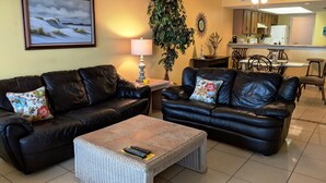 A living room with two black leather sofas, a coffee table, a painting, a lamp, and a potted plant. - Right Price in Paradise! Luxury Ocean Front (South Padre Island)