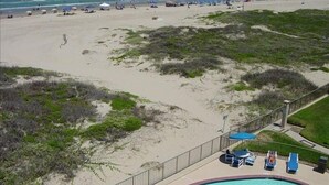 A beach view with a pool area, including lounge chairs and a small table. - Right Price in Paradise! Luxury Ocean Front (South Padre Island)