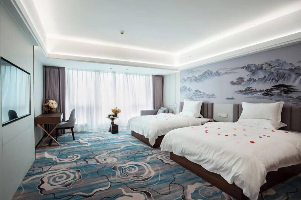Une chambre d’hôtel avec deux lits, un bureau et une chaise.