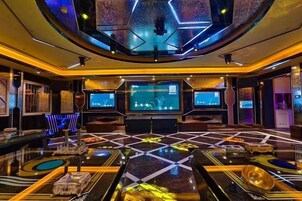 Un interior moderno con una zona de estar central, varias pantallas y un diseño geométrico para el suelo.