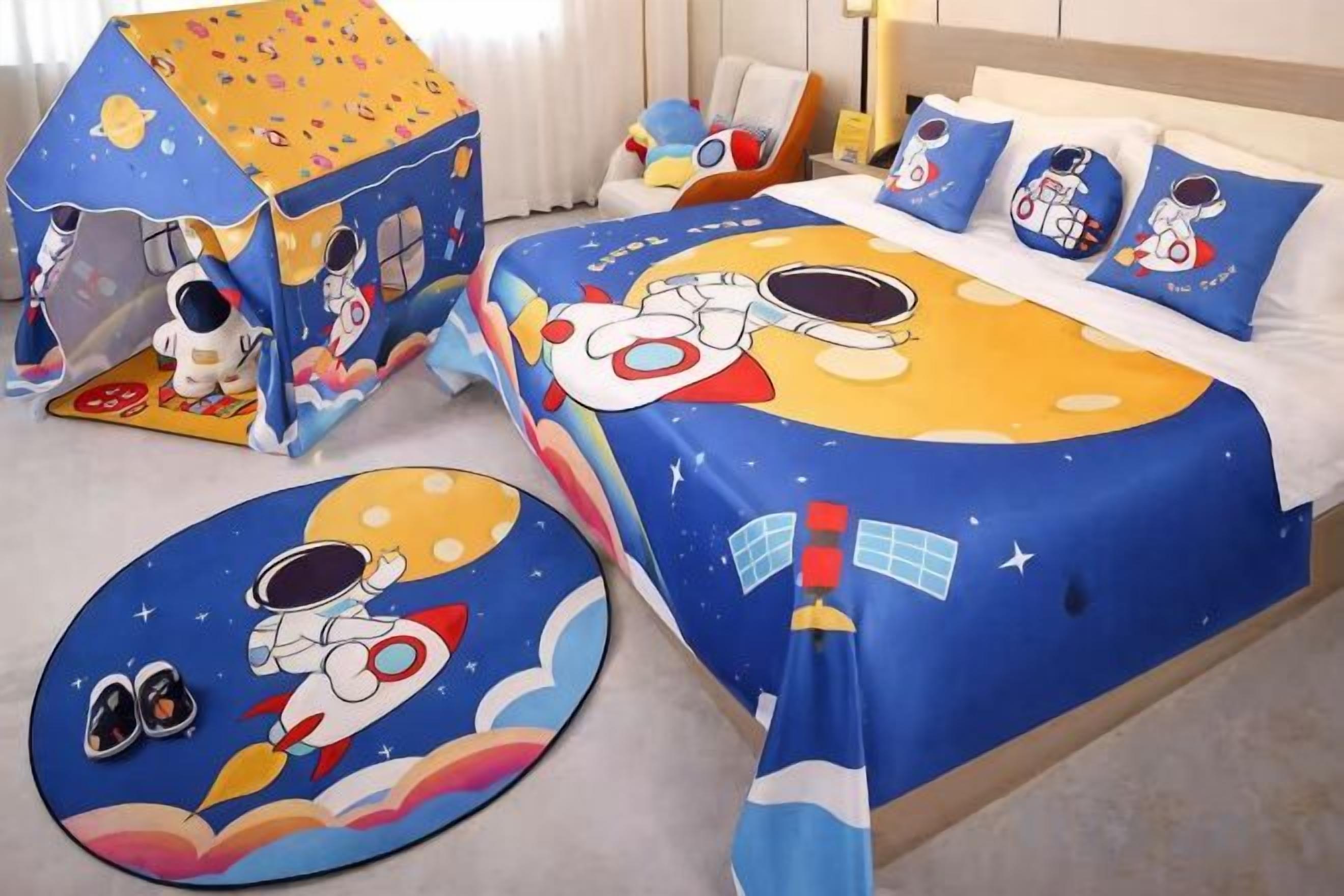 A child's bedroom with a space-themed bedspread, pillows, and a playhouse.