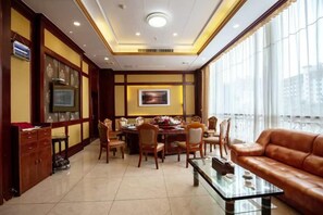 A hotel dining area with a table set for four, a sofa, and a television on the left.