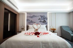 A hotel room with a bed, a painting on the wall, a nightstand, a chair, and a door.