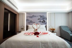 A hotel room with a bed, a painting on the wall, a nightstand, a chair, and a door.