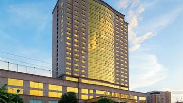 Un hotel moderno de gran altura con fachada curva, varios pisos y una entrada destacada con señalización.