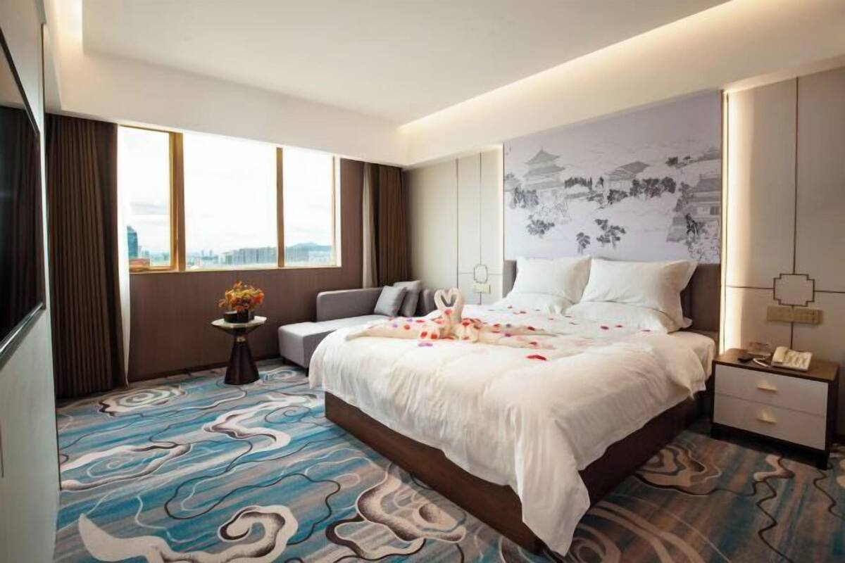 Une chambre d’hôtel comprenant un lit, une table de chevet, une commode, une fenêtre et un mur orné d’une fresque.