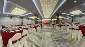 A banquet hall with round tables, white chairs, and a marble floor.