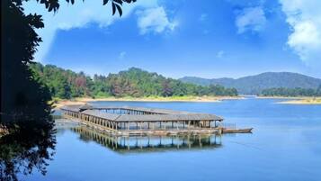 A wooden pier extending into calm water, surrounded by forested hills.
