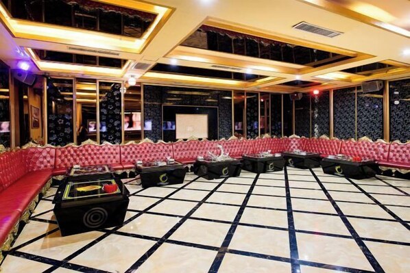 A spacious room with a red upholstered sofa, black coffee tables, and a tiled floor.