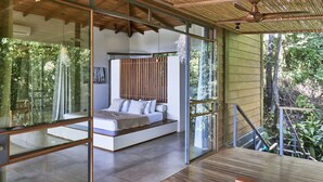 Ein modernes Schlafzimmer mit Glaswand, Holzboden und Blick ins Freie.