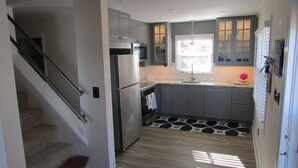 Une cuisine moderne avec des meubles gris, des appareils en acier inoxydable et un carrelage décoratif.