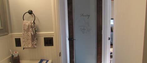 A bathroom with a towel rack, toothbrush holder, and a door with a 'Pantry' sign.