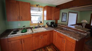 A compact kitchen with wooden cabinets, a granite countertop, a sink, and a stove.
