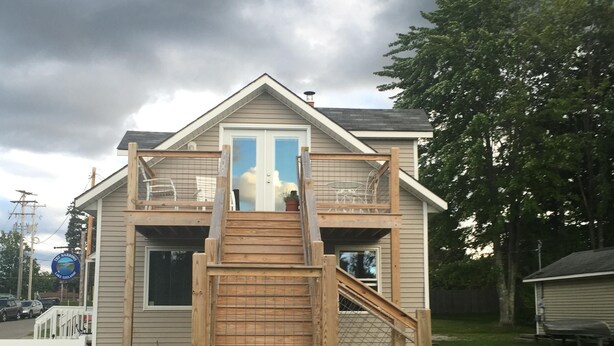 A two-story house with a wooden staircase leading to a balcony.