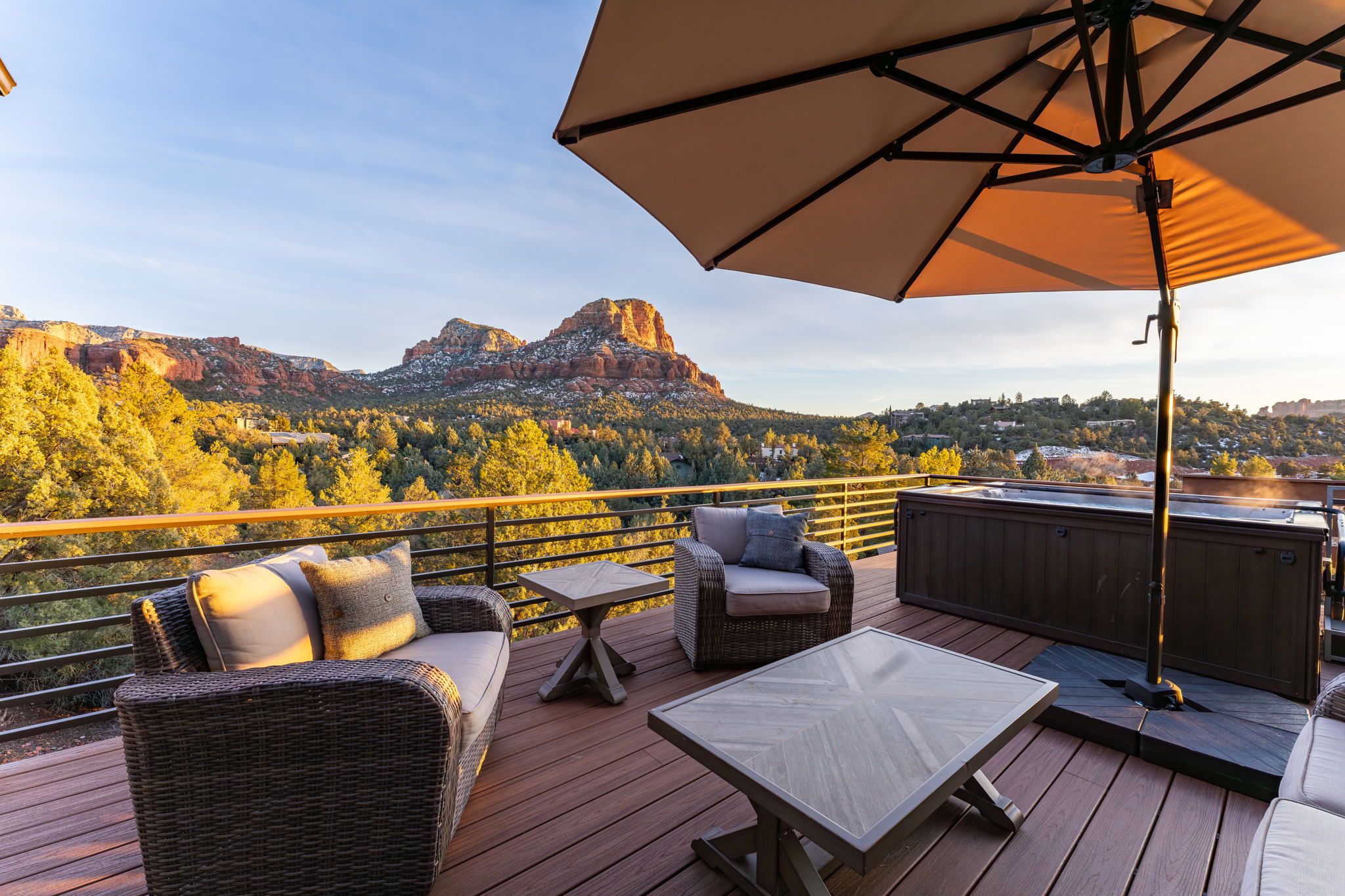 A deck with outdoor furniture, a hot tub, and a view of a mountain range.