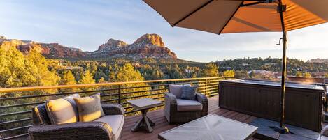 A deck with outdoor furniture, a hot tub, and a view of a mountain range.