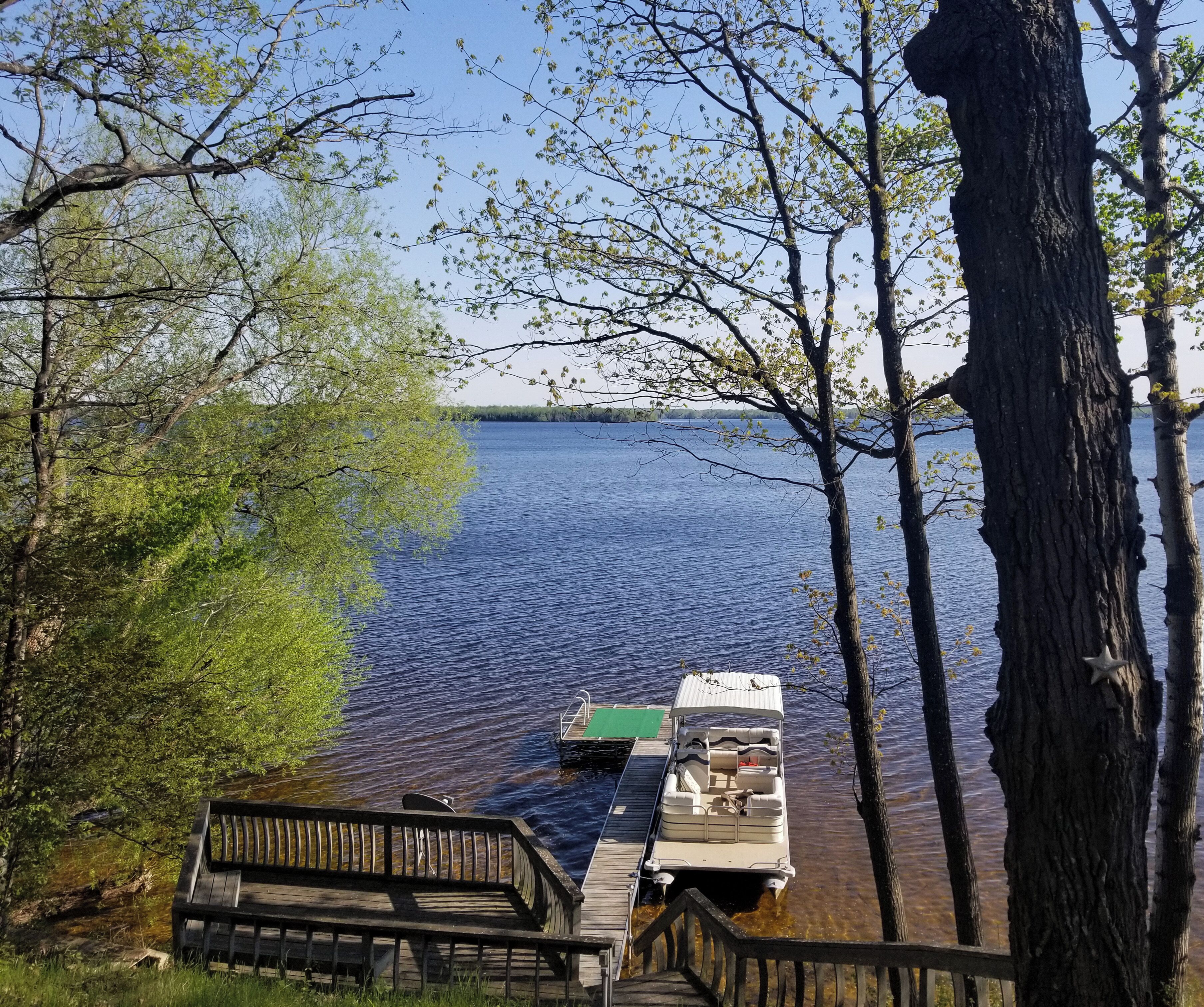 A dock extending into a calm lake, surrounded by trees.