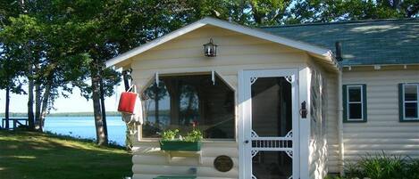 A small cabin with a porch, a bench, and a red mailbox.