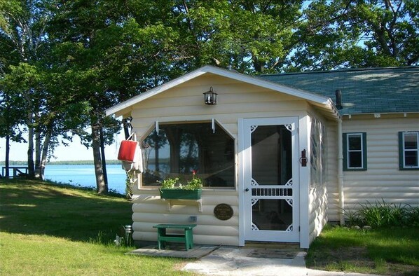 A small cabin with a porch, a bench, and a red mailbox.
