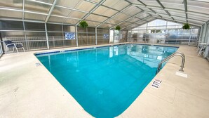 An indoor swimming pool with a clear blue water, surrounded by a covered area with metal railings and signs indicating no lifeguard on duty. - 2BR OF Crescent Beach. Enclosed pool. Great location! (North Myrtle Beach)