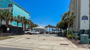 A hotel with a turquoise exterior, a gated parking area, and a sign for Crescent Sands. - 2BR OF Crescent Beach. Enclosed pool. Great location! (North Myrtle Beach)